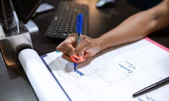 Small business owner writing a business proposal at a desk with a laptop and notes.
