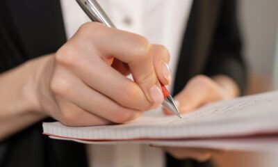 Person writing meeting notes in a notebook, showing how to write meeting notes clearly
