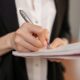 Person writing meeting notes in a notebook, showing how to write meeting notes clearly