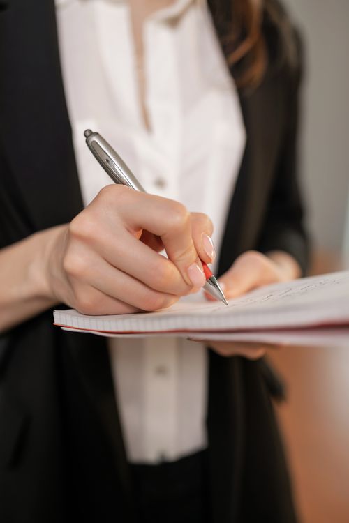 Person writing meeting notes in a notebook, showing how to write meeting notes clearly